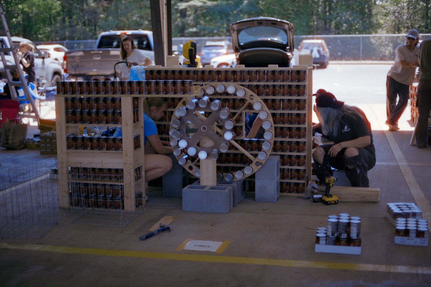 People collaborate on a community sculpture made from canned goods.