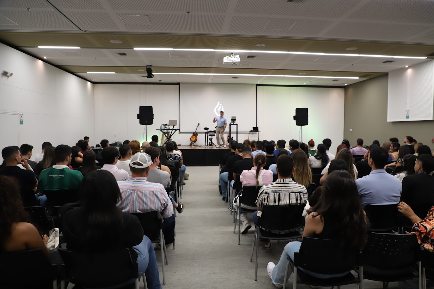 A speaker presents to an attentive audience in a modern auditorium.