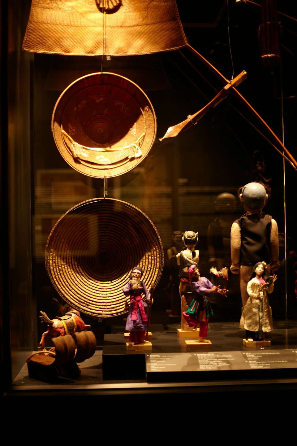 Cultural artifacts displayed in a museum case with figurines and baskets.