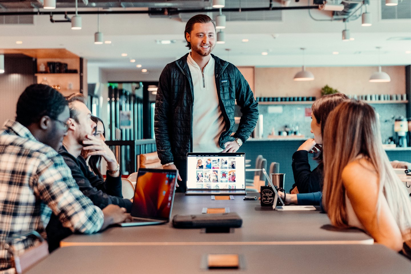 Diverse professionals collaborating around a conference table with open laptops.