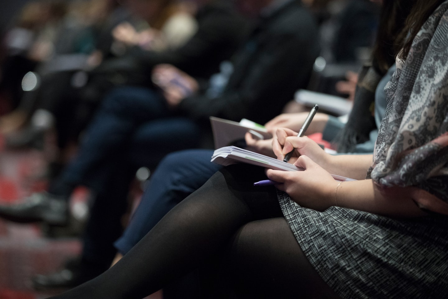 Woman taking notes at a conference with a pen.