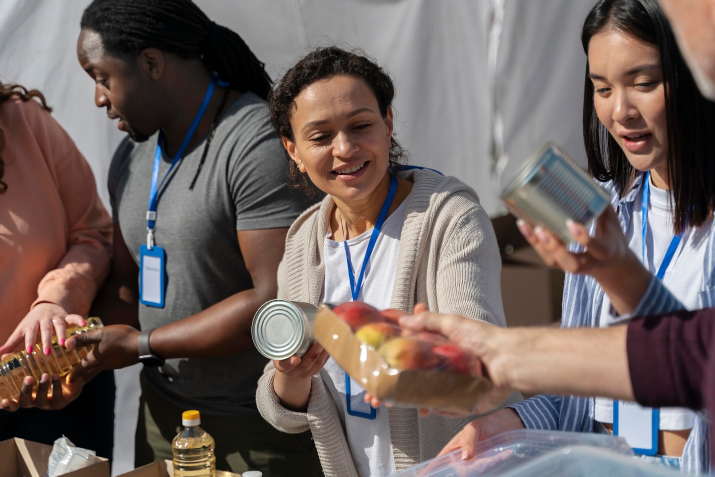 Volunteers sort and distribute food items at an outdoor charity event.