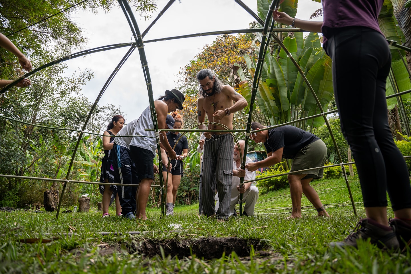 People work together to tie bamboo poles into a dome.