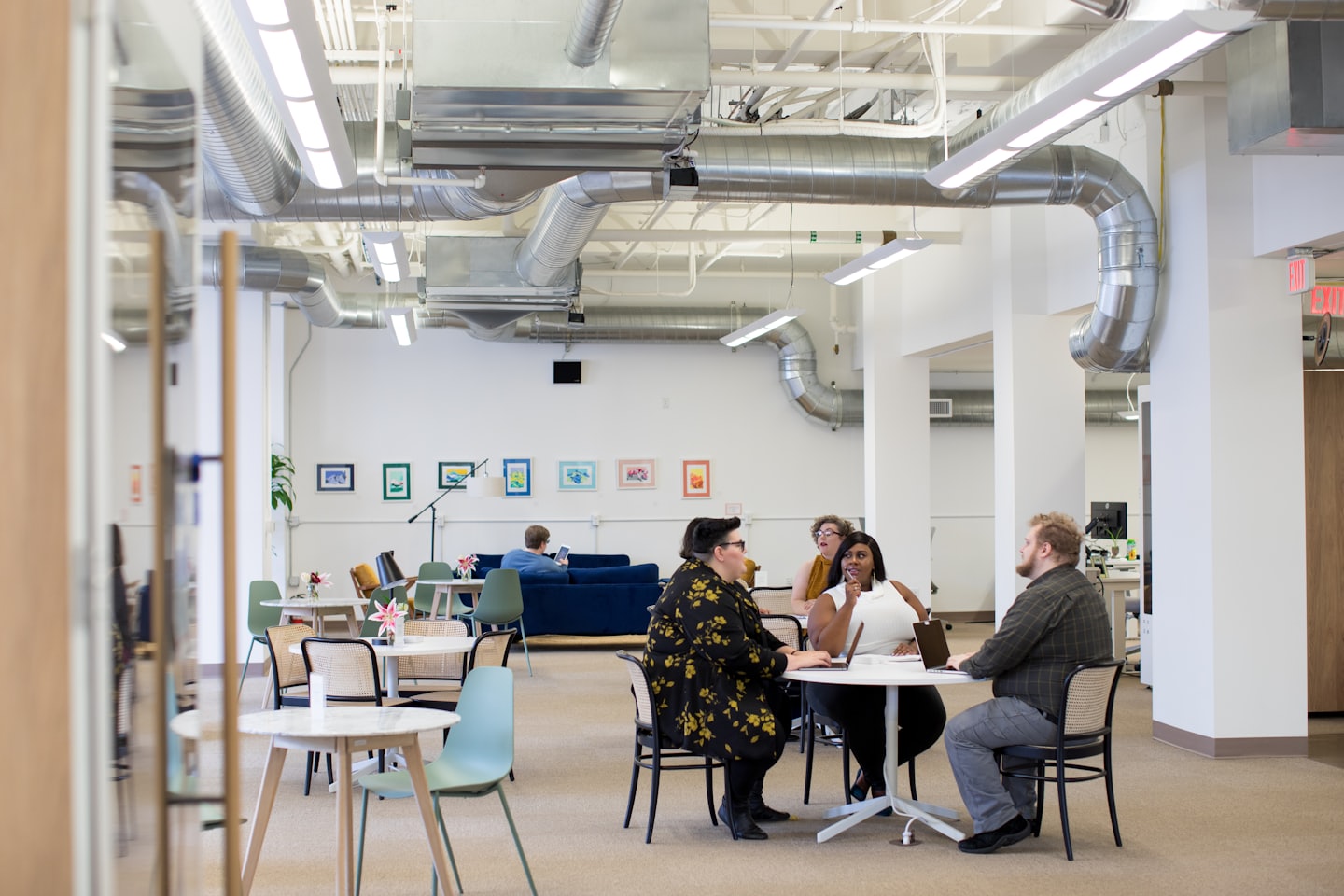 Diverse team collaborates around table with laptops in bright office.