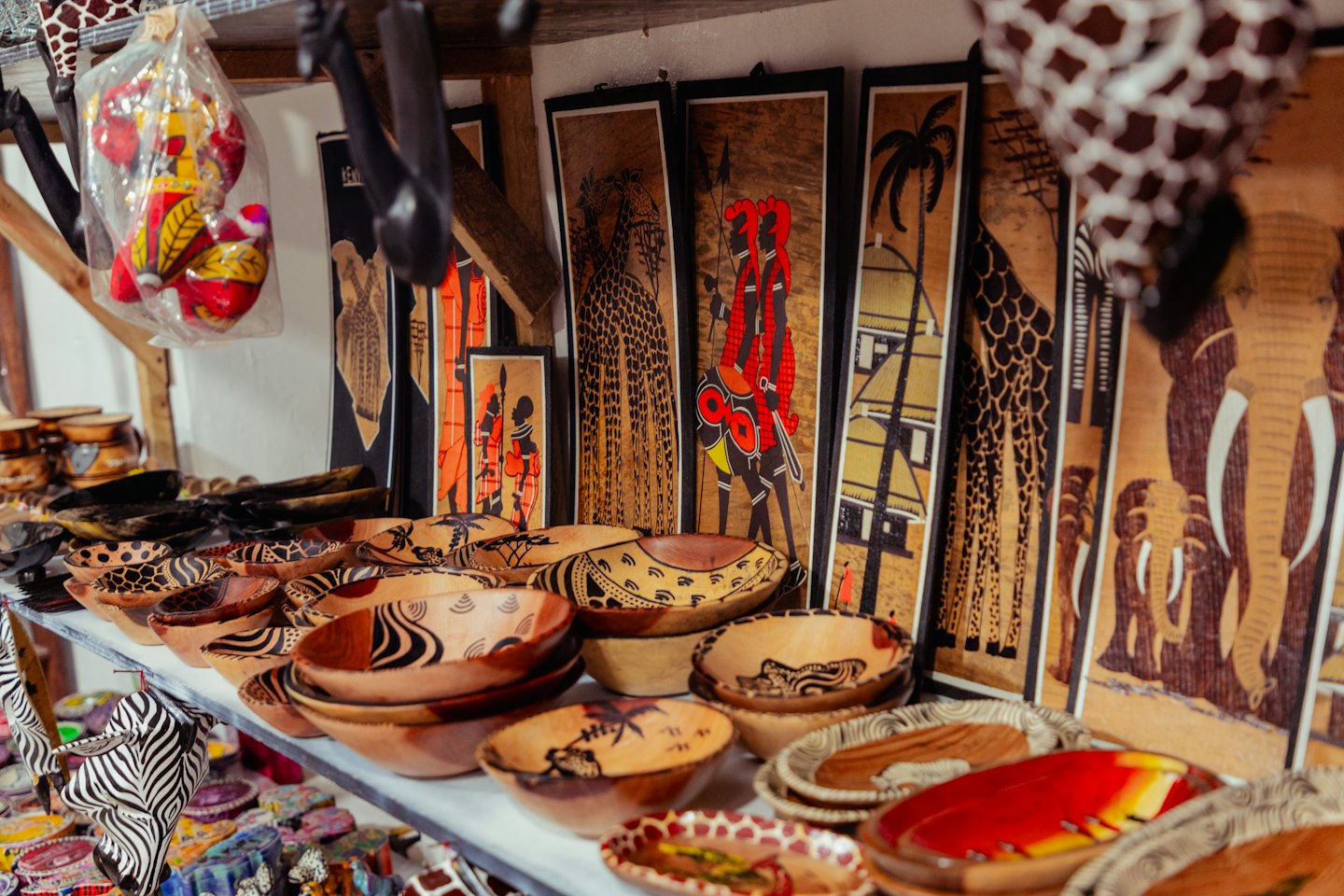 African handicrafts including carved wooden bowls and framed paintings.